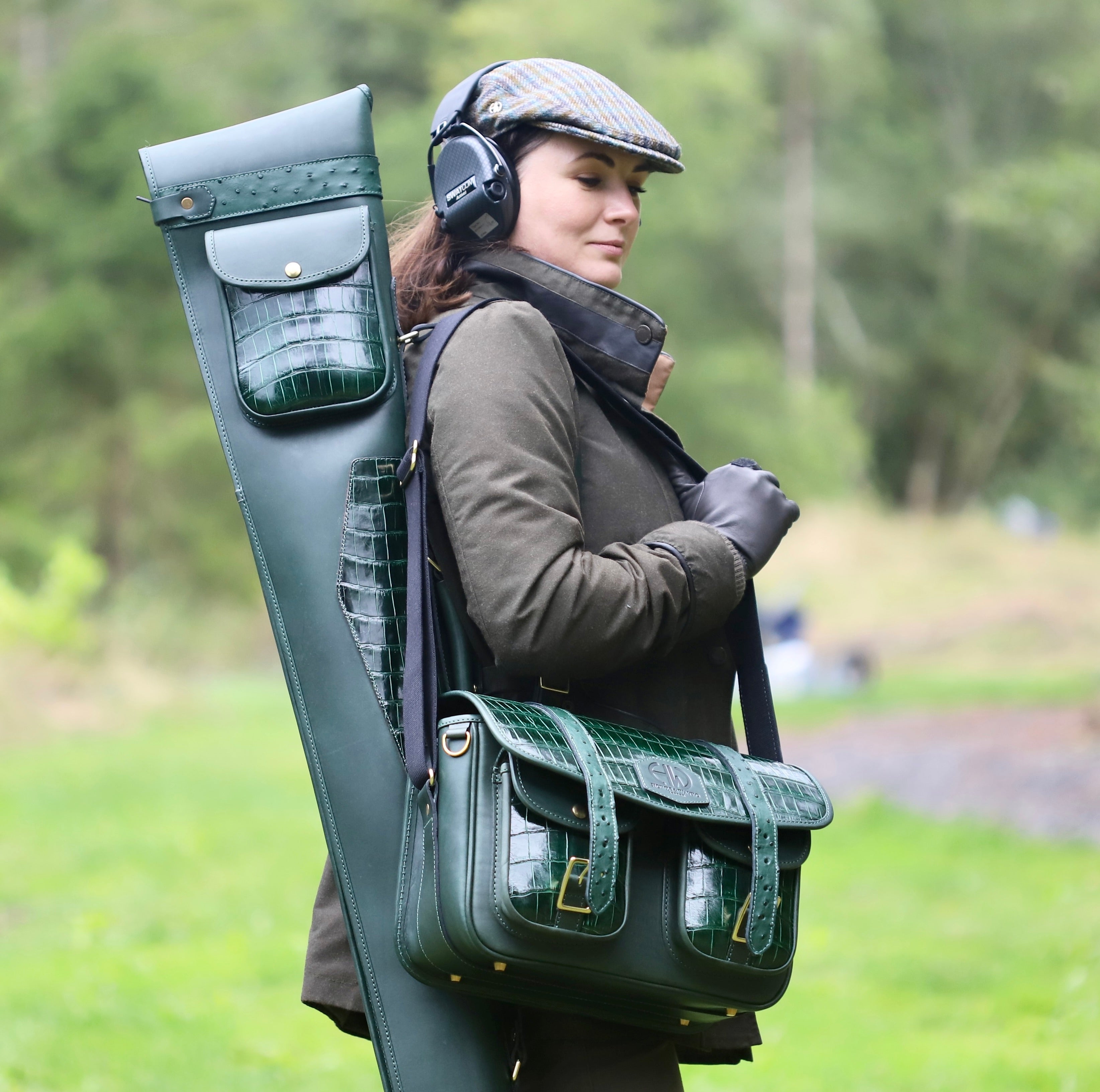 shooting season - a woman wearing shooting accessories in a field including cartridge bag, gun slip and tweed cap