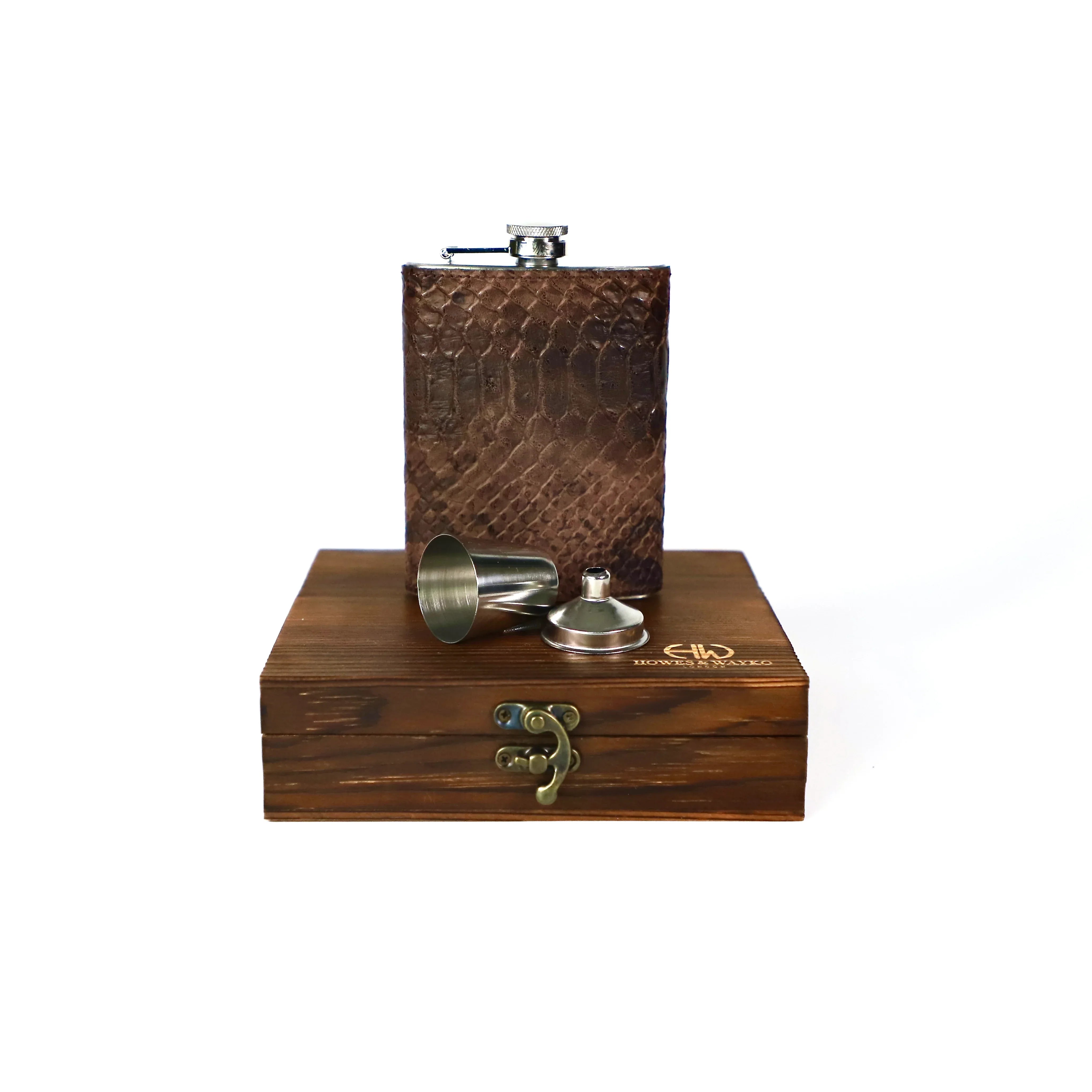 Stainless Flask covered with a snake pattern and accessories on a wooden stand with a white background