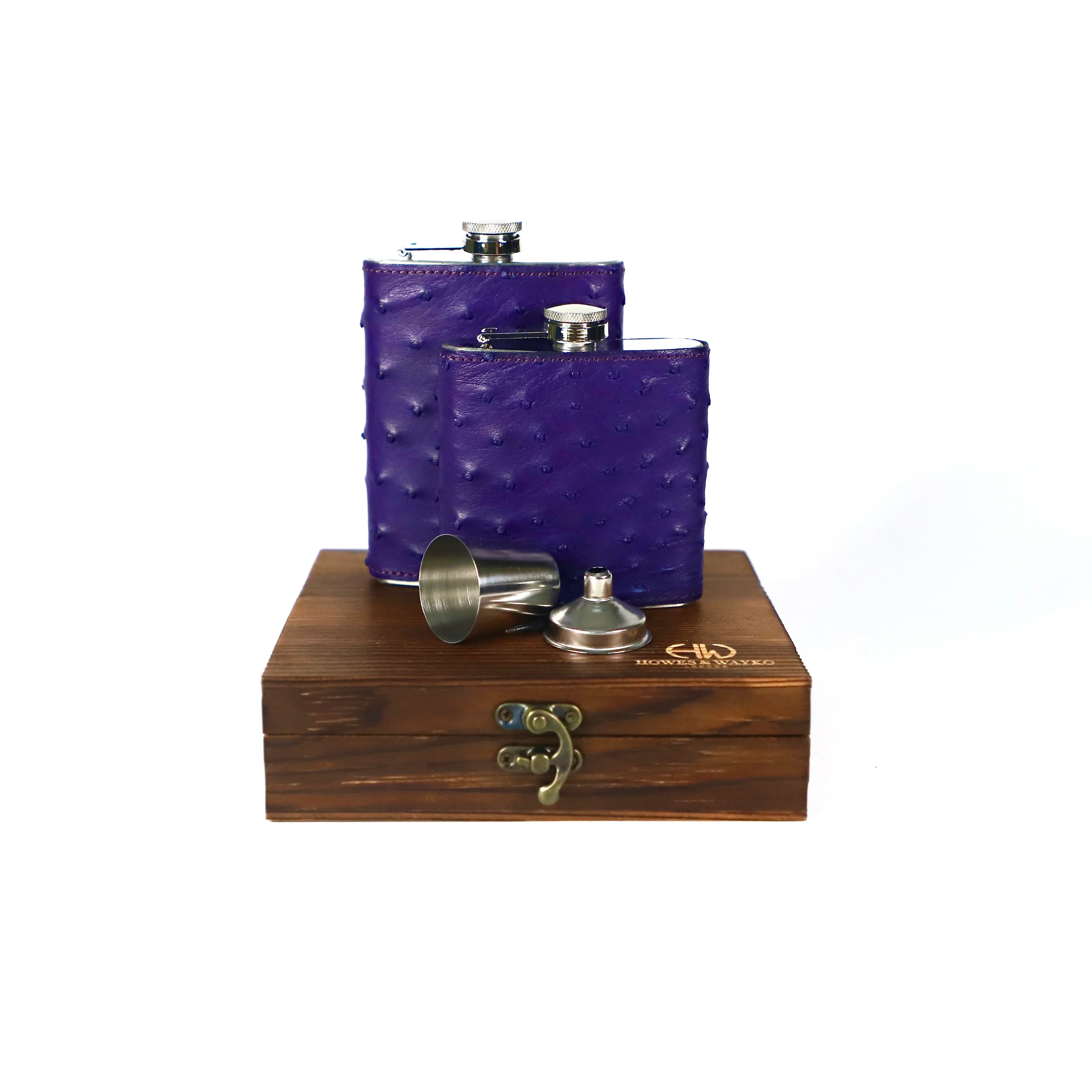 Two purple Ostrich leather flasks are displayed on a wooden box on a white background