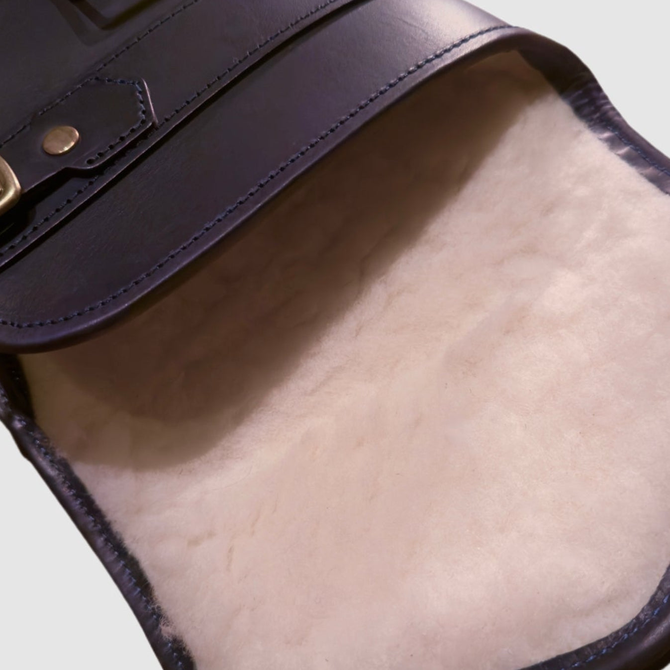 Close-up of a leather range slip with a beige sheep skin lining on a light background