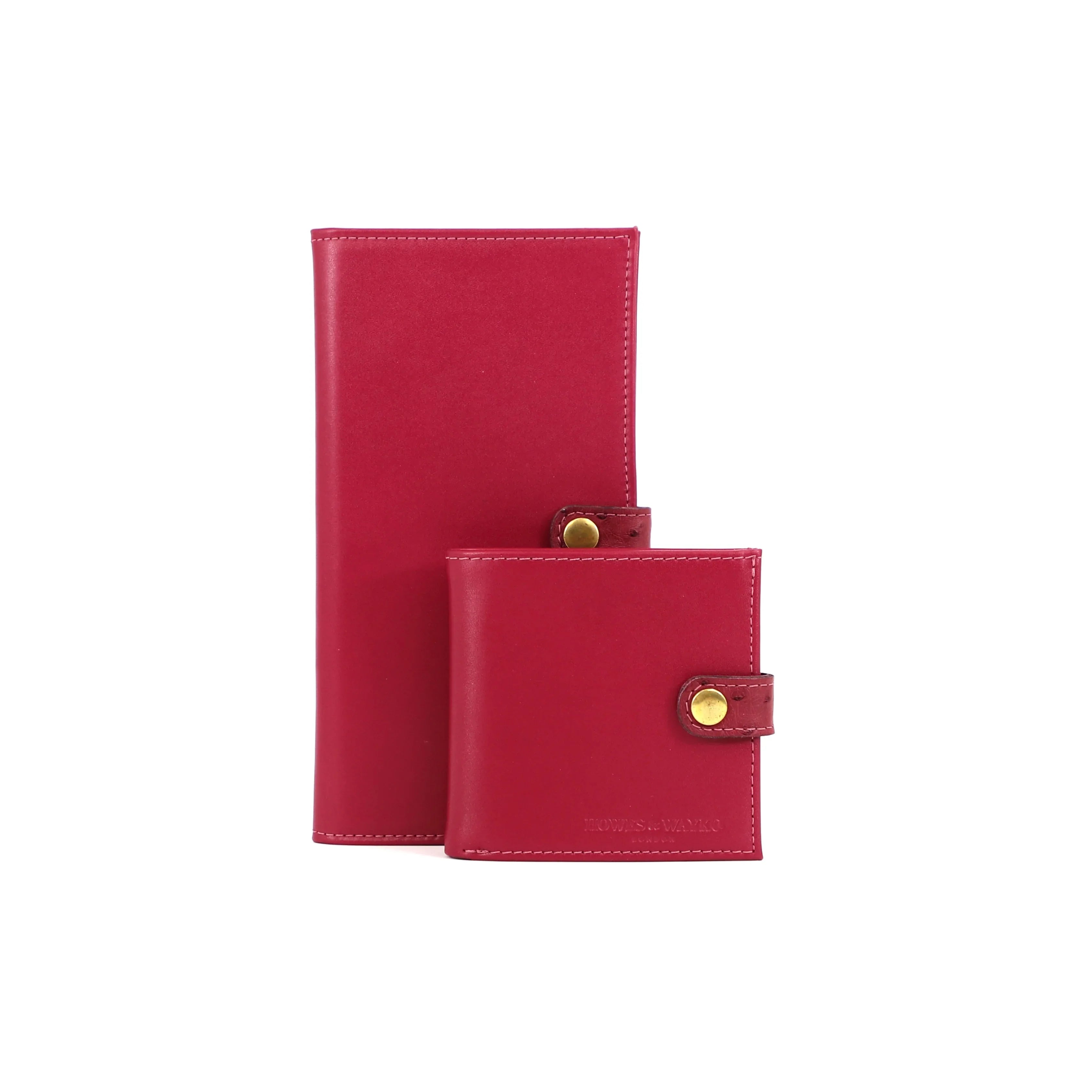 Two pink leather certificate wallets, accentuated with a matching Ostrich clasp and gold snap, on a white background