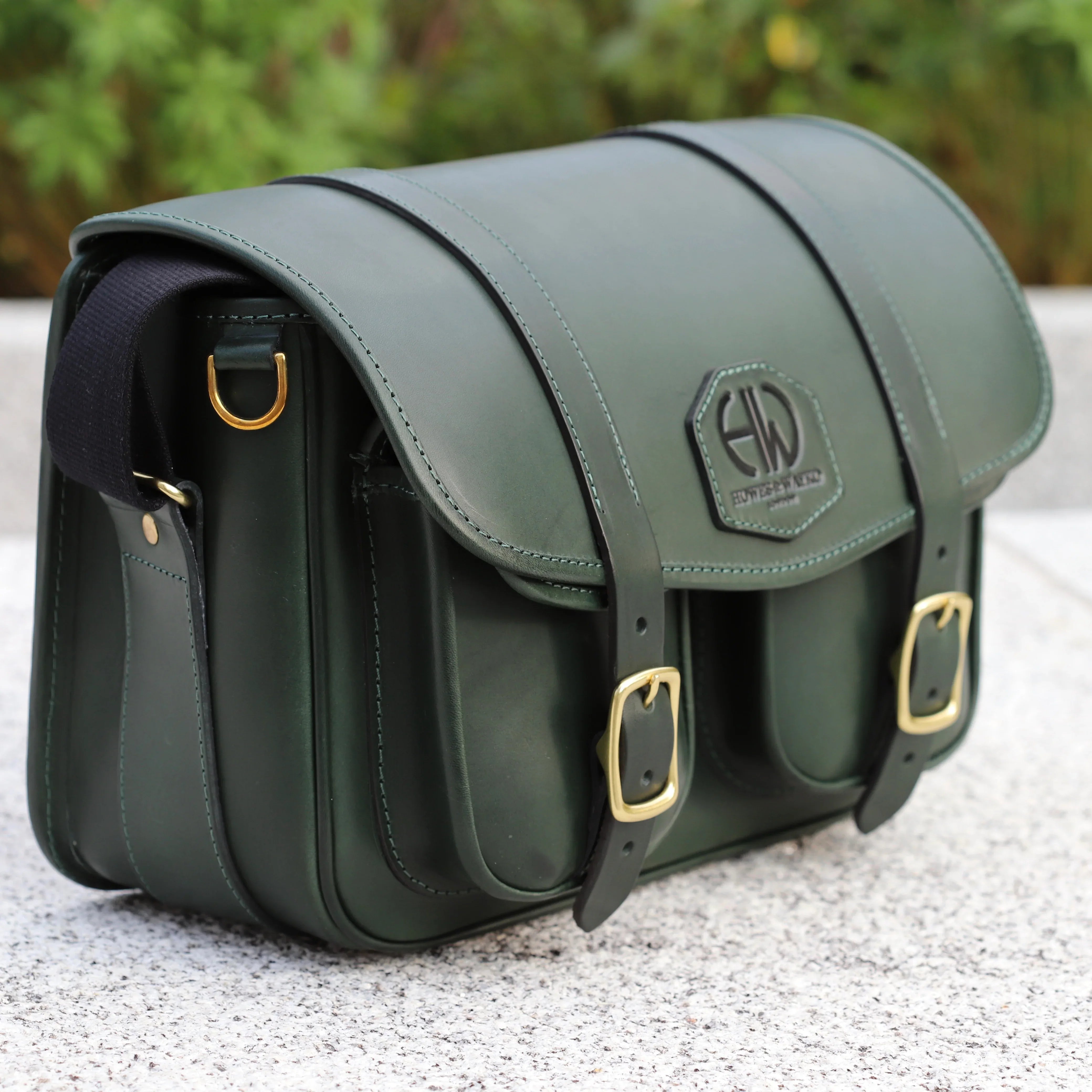 HERA-EDEN HUNTERS GREEN CARTRIDGE BAG OTHER SIDE VIEW OF BAG PLACED ON WALL OUTDOORS