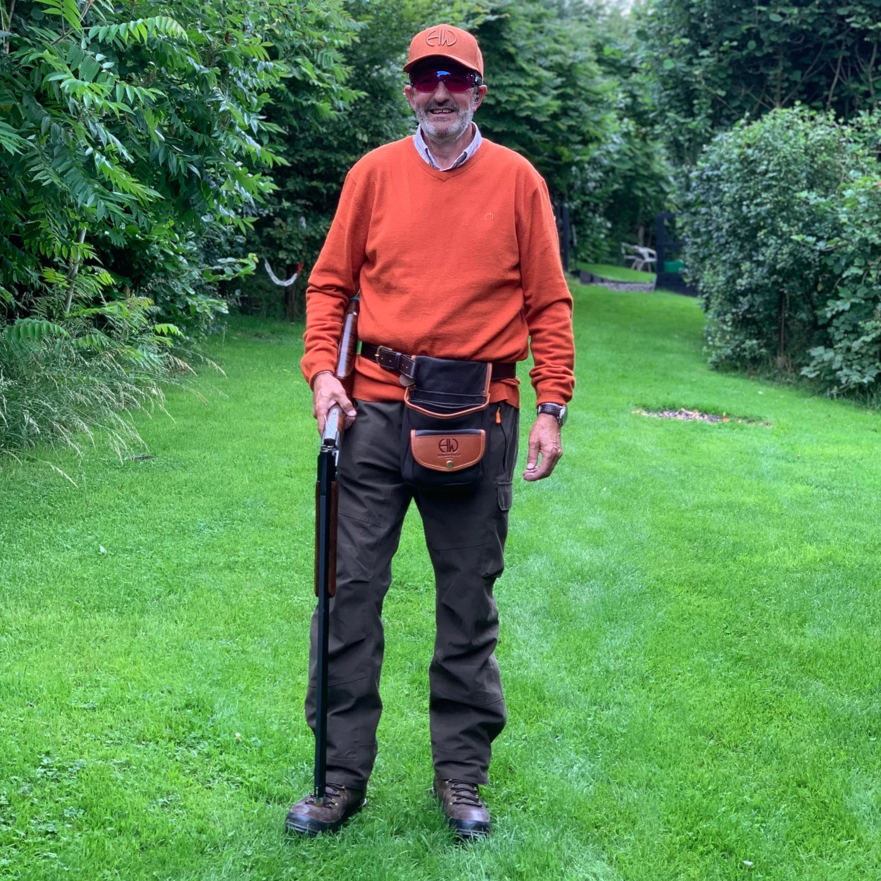 Iris Orange Shooting Baseball Cap - Shooting Gear adorned in the outdoors on a person that is wearing a matching colour orange jumping and other shooting gear