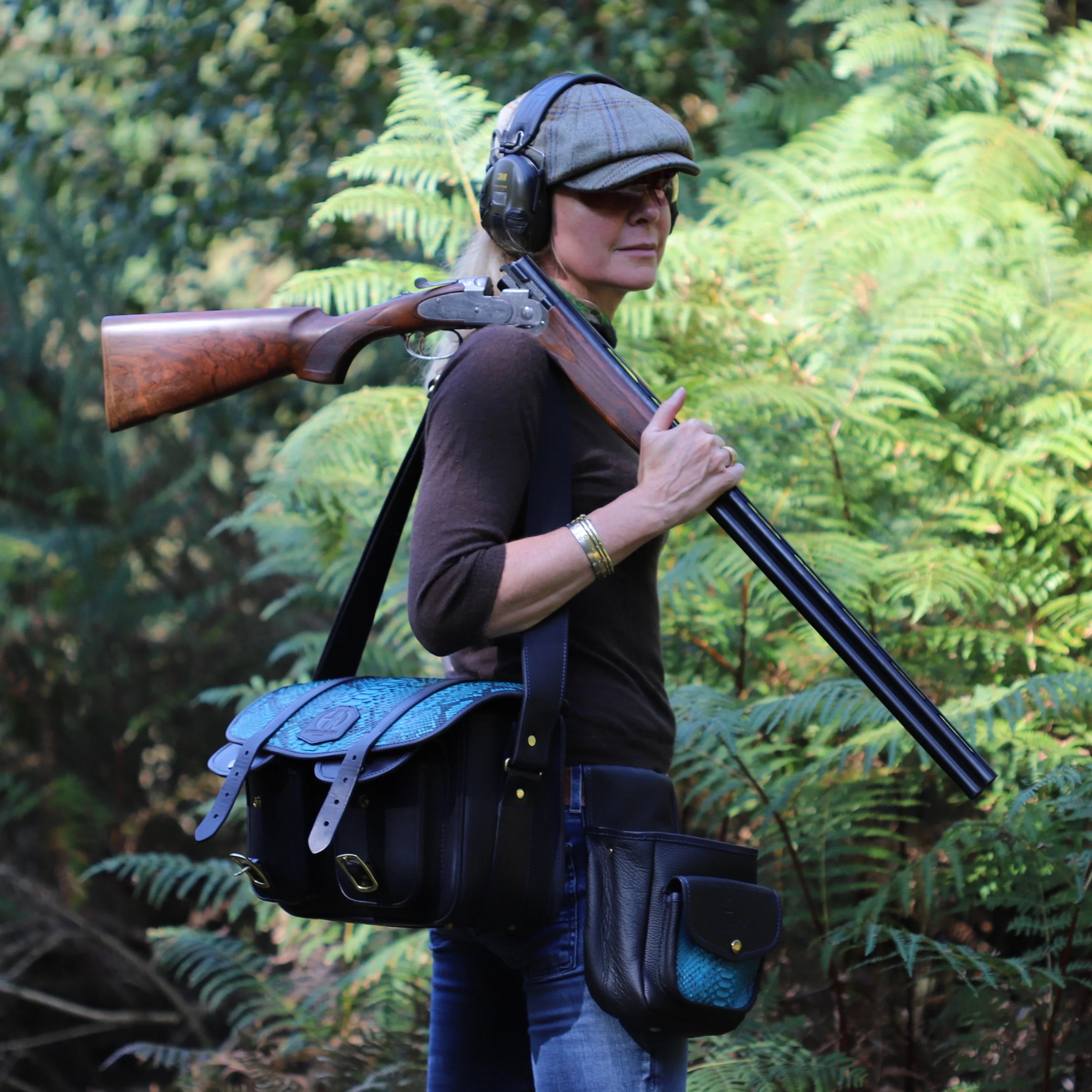 HERA NAVY WITH BLUE SNAKE CARTRIDGE BAG ADORNED ON A PERSON IN THE FIELD WITH OTHER SHOOTING ACCESSIORIES ON