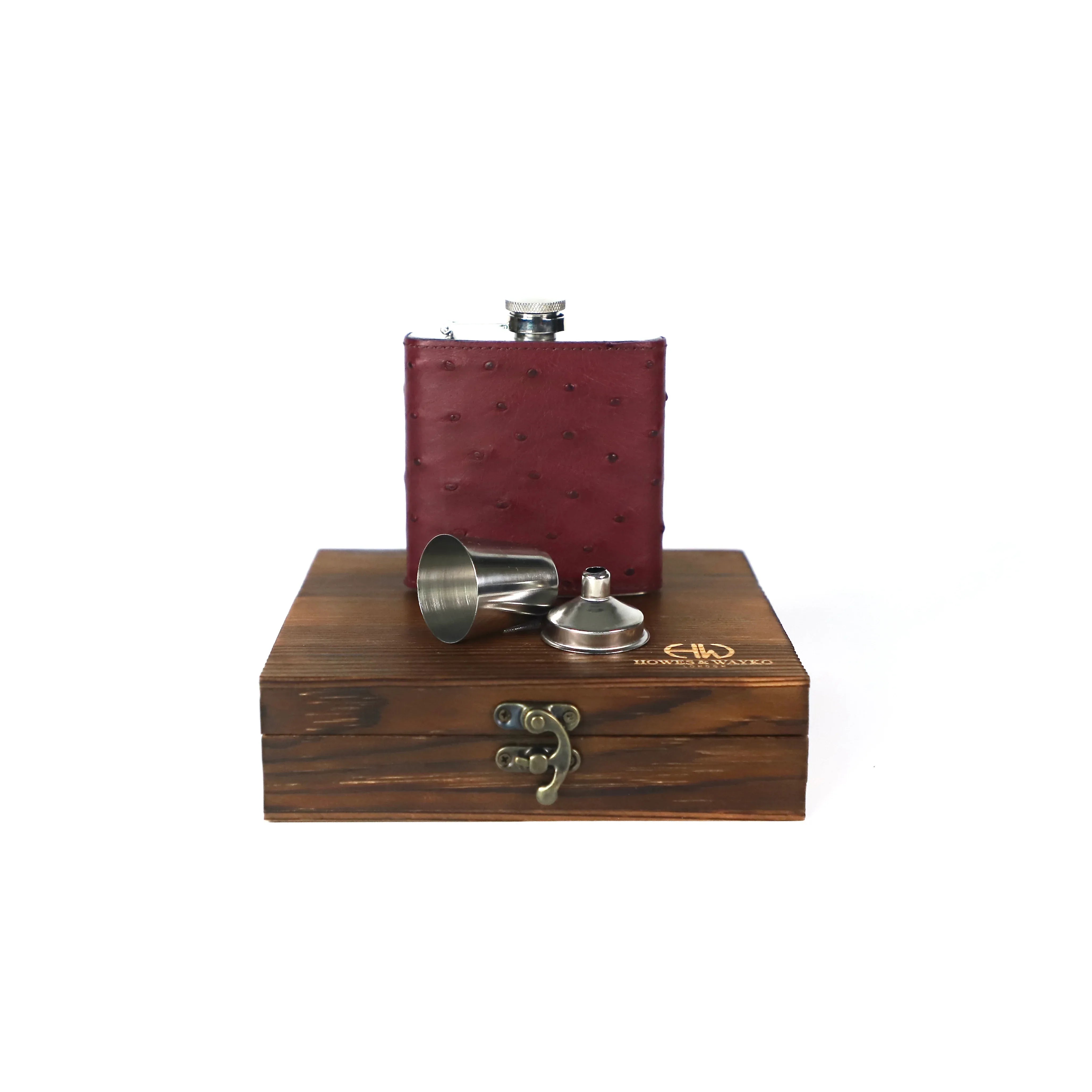 Burgundy leather flask with silver cap and two additional silver flasks on a wooden stand with Howes and Wayko branding.