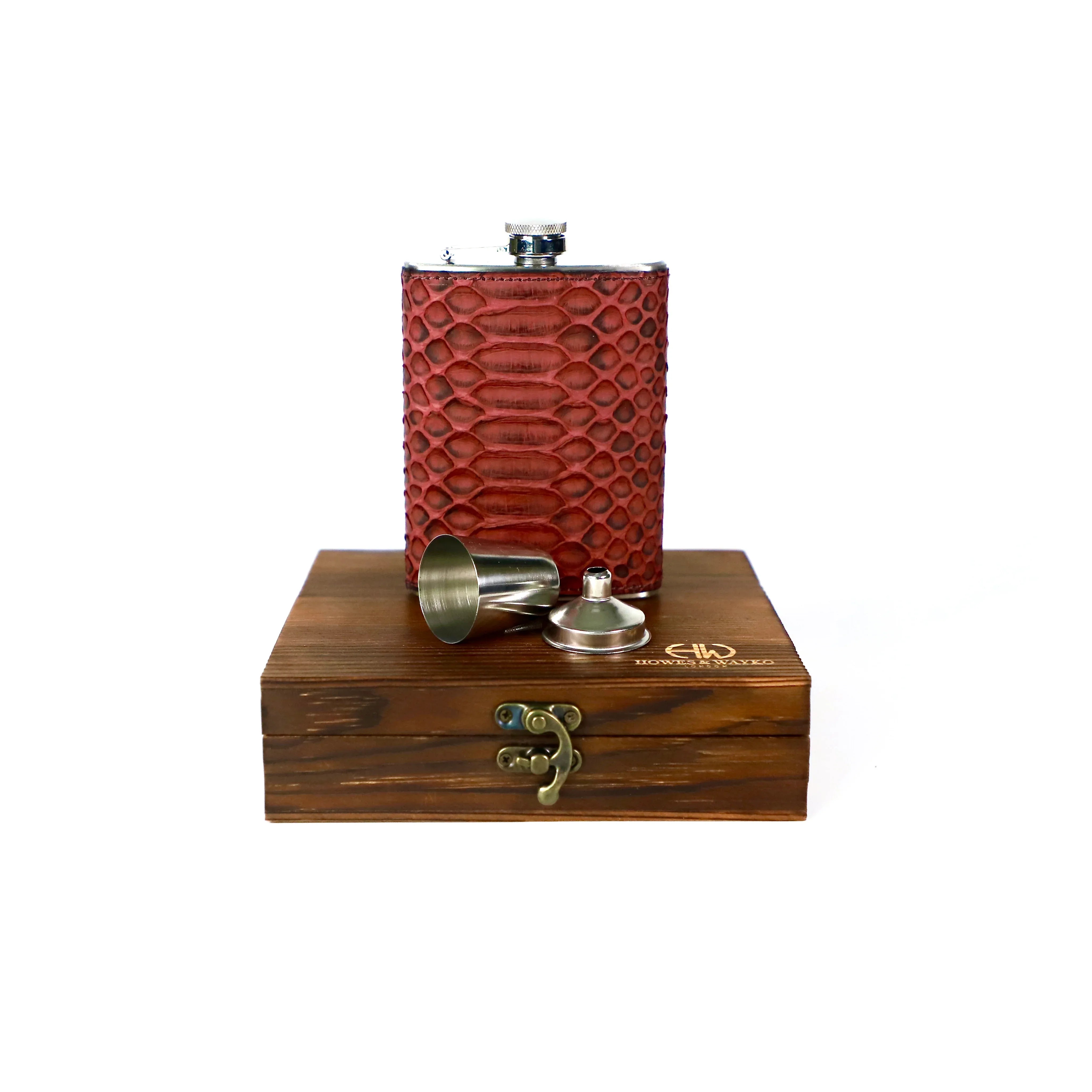 Burgundy textured flask with silver cap, with a shot glass and a funnel on a wooden stand with a visible brand logo.