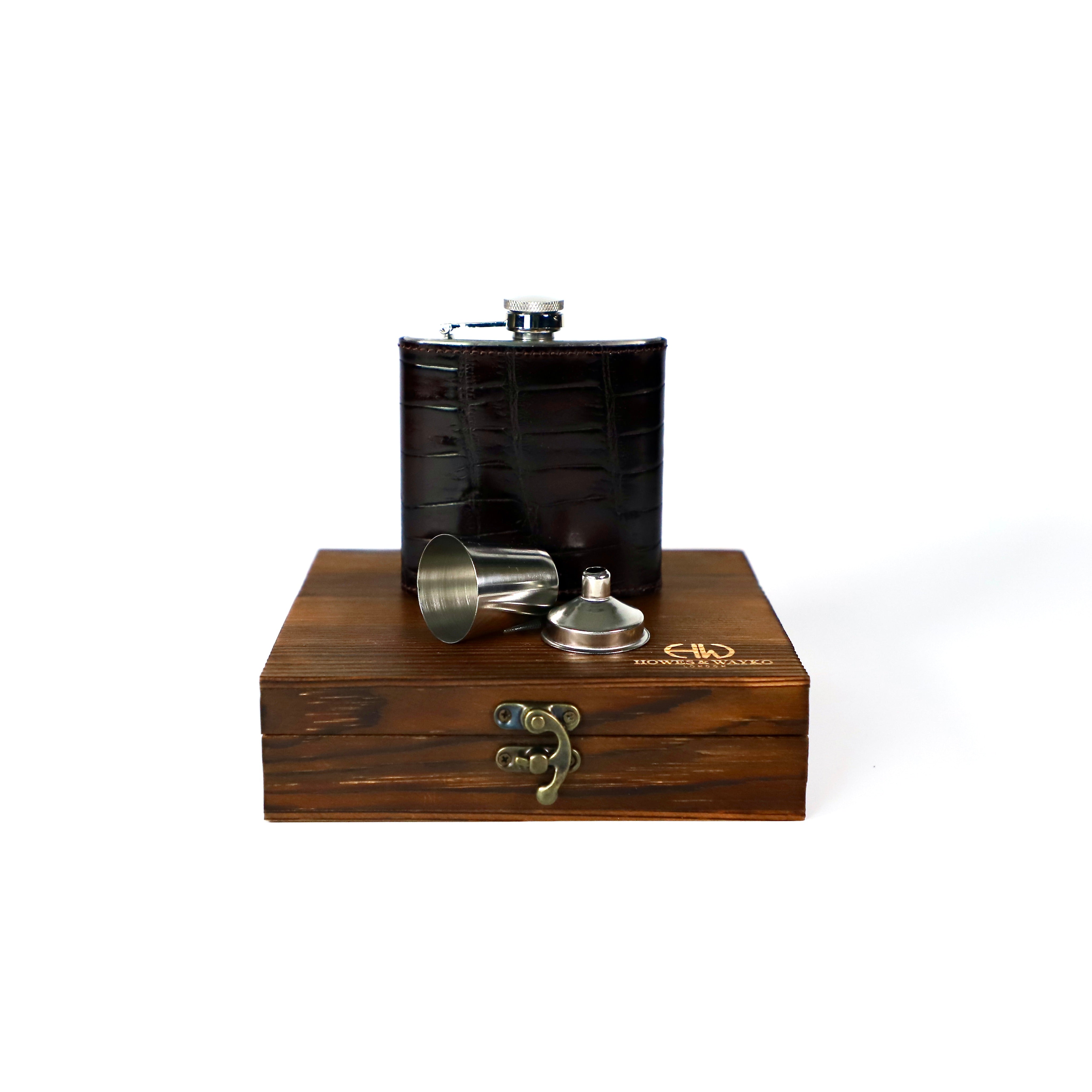 6oz Stainless steel flask, covered in brown  embossed leather, displayed on a wooden gift box displaying Howes and Wayko logo