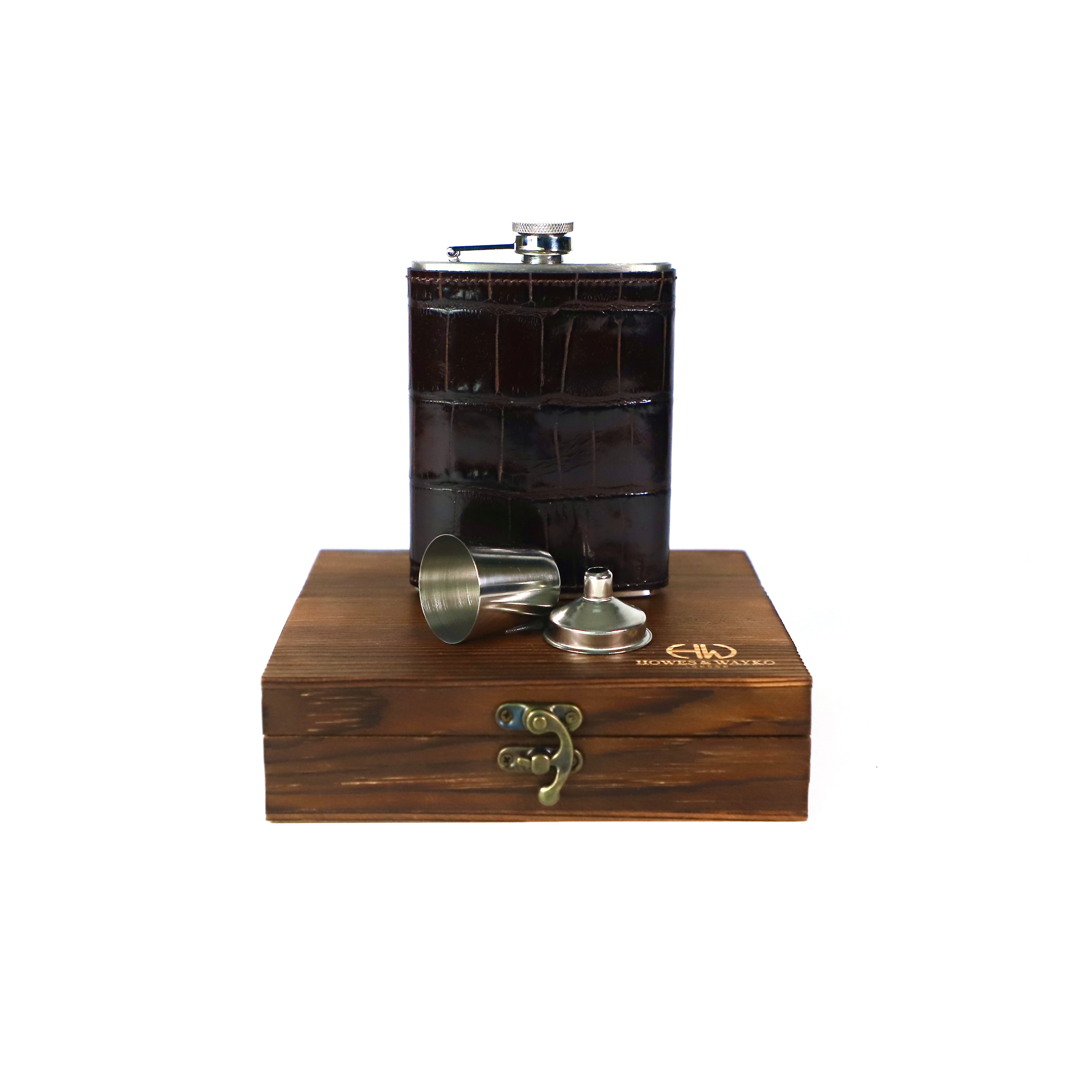 Brown leather flask with silver components on a wooden base with a Howes and Wayko logo.