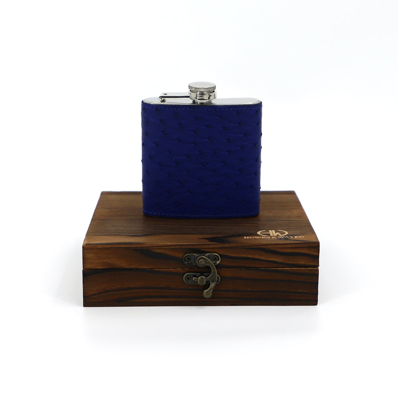 dark blue hip flask sitting on top of wooden casing with H&W logo