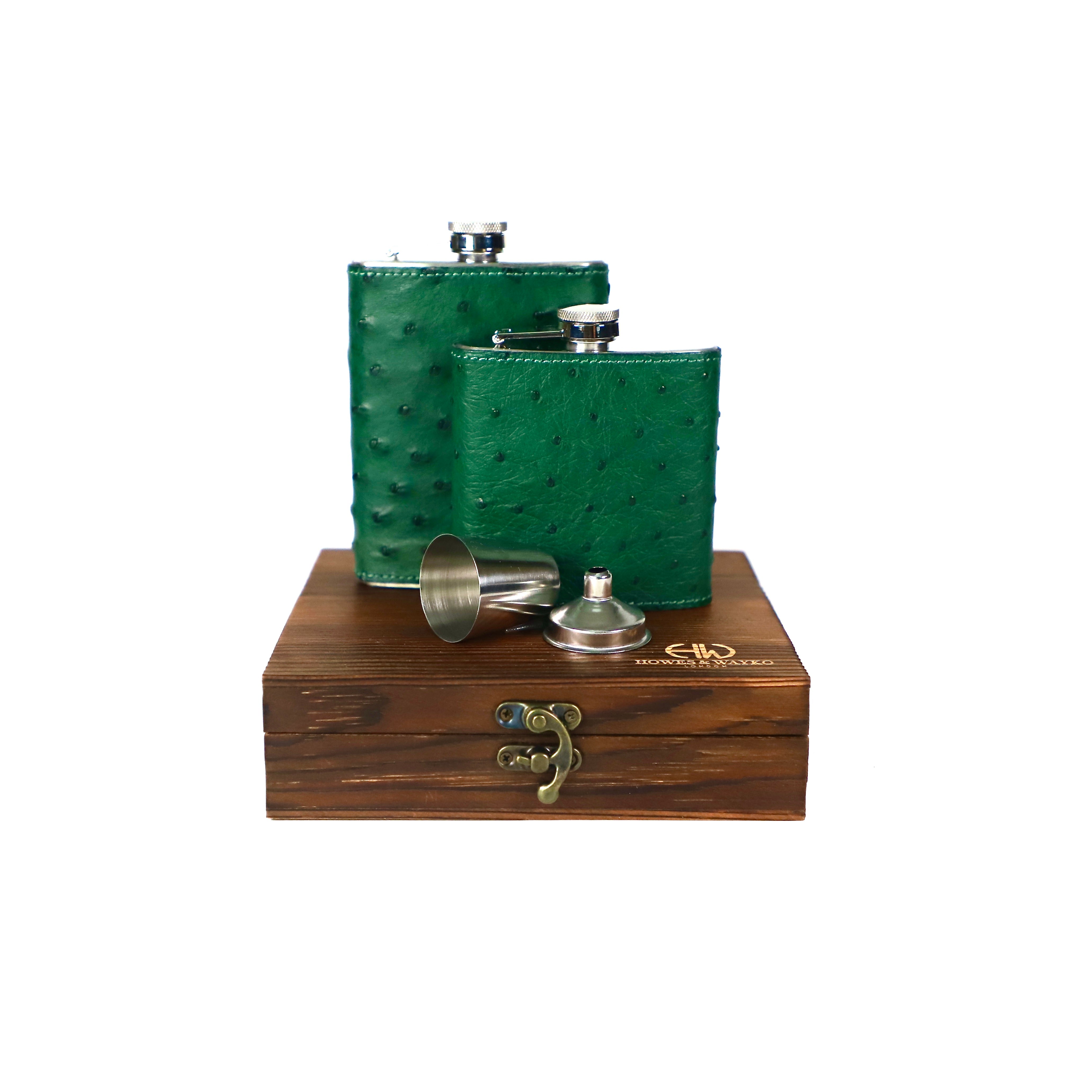 Two green stainless  steel flasks, covered in green Ostrich leather and displayed on a brown wooden gift box against a white background