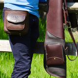 Hella Madison Shotgun Cartridge Pouch, Shooting Accessories on a persons hip in a field with a wooden fence and person holding gun slip