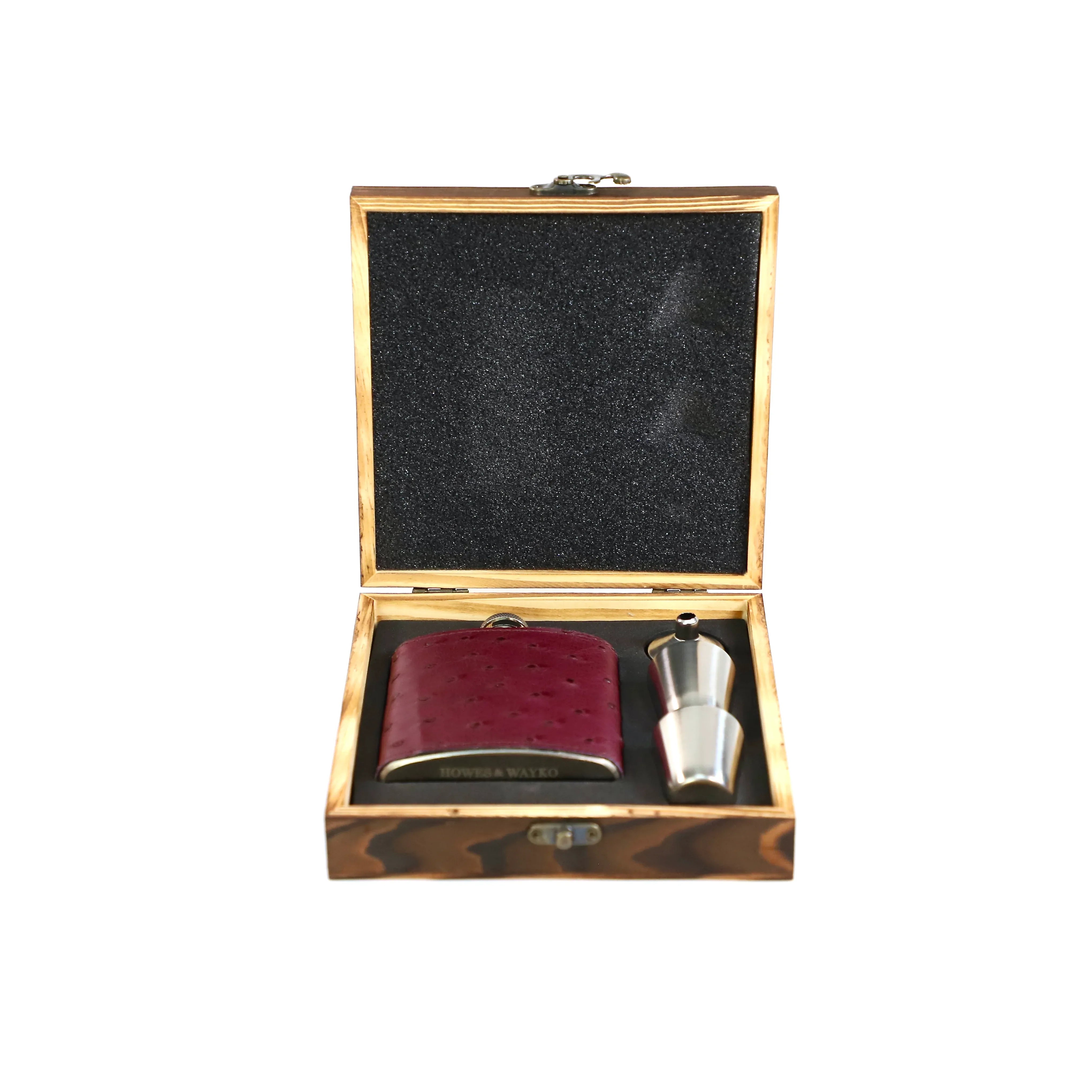 Burgundy Ostrich leather flask with a pair of shot glass and a stainless steel shot glass and funnel in  a wooden box on a white backgroundl 