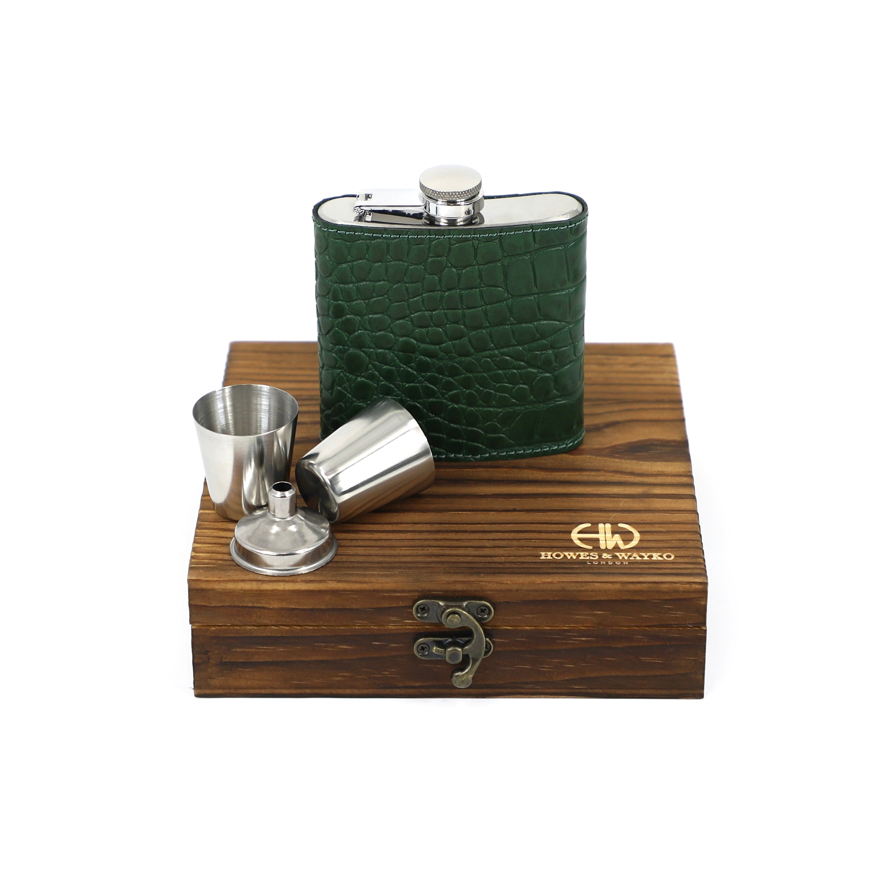 top view of green croc-embossed leather hip flask on top of wooden case next to shot glasses
