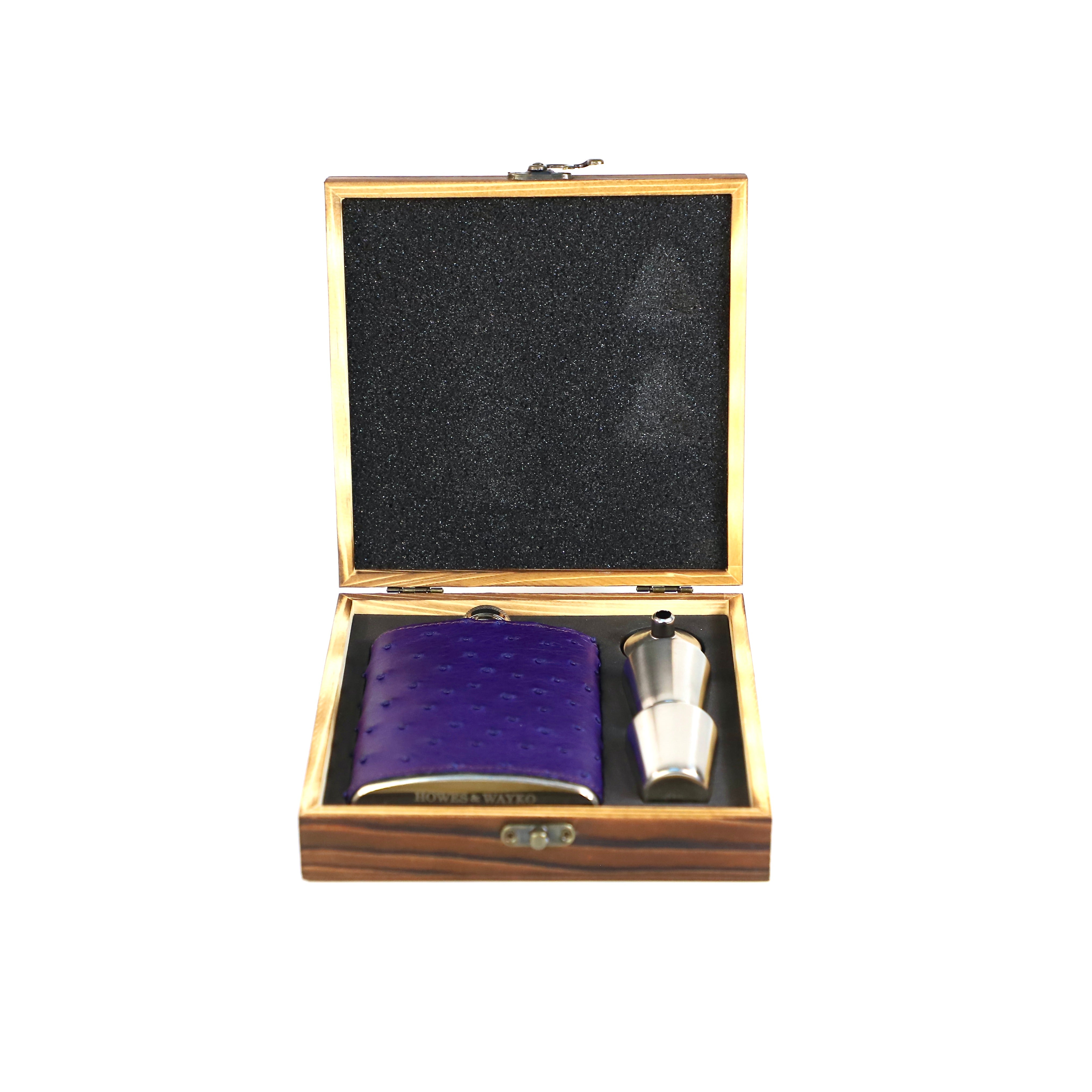 Purple pocket flask and silver funnel in a wooden box on a white background