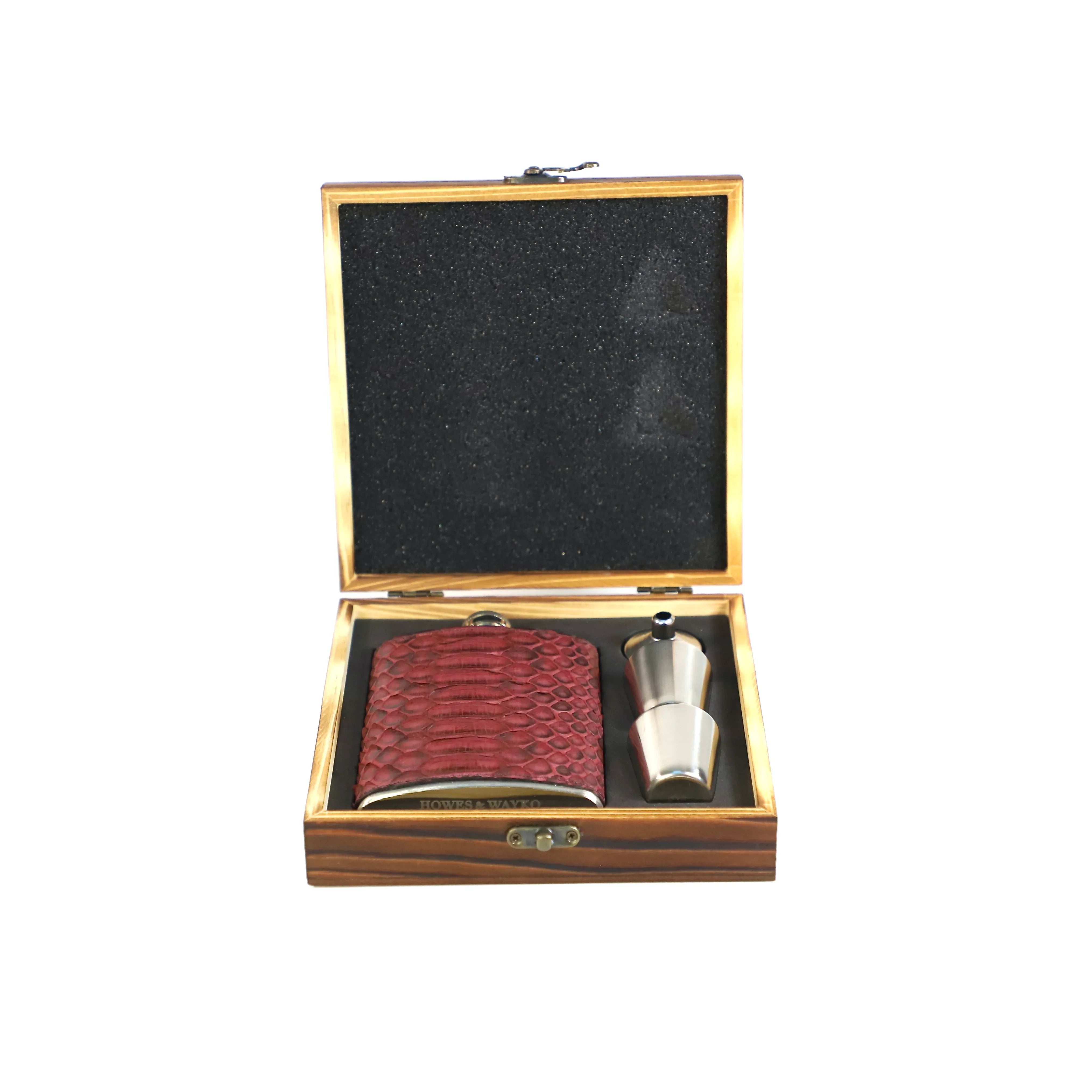 Wooden box with a burgundy snake leather flask and a silver shot glass on a white background