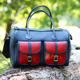 the erin yanik leather range bag sitting on a log front facing, with blurred out greenery in the background