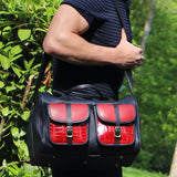 a leather range bag over a persons shoulder and bushes and greenery in the outdoor background