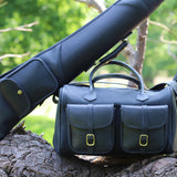 Leto Navy Gun Slip - Fleece Lined Leather Gun Protector showcased on a tree/log with greenery in the background and matching cartridge bag underneath the gun slip