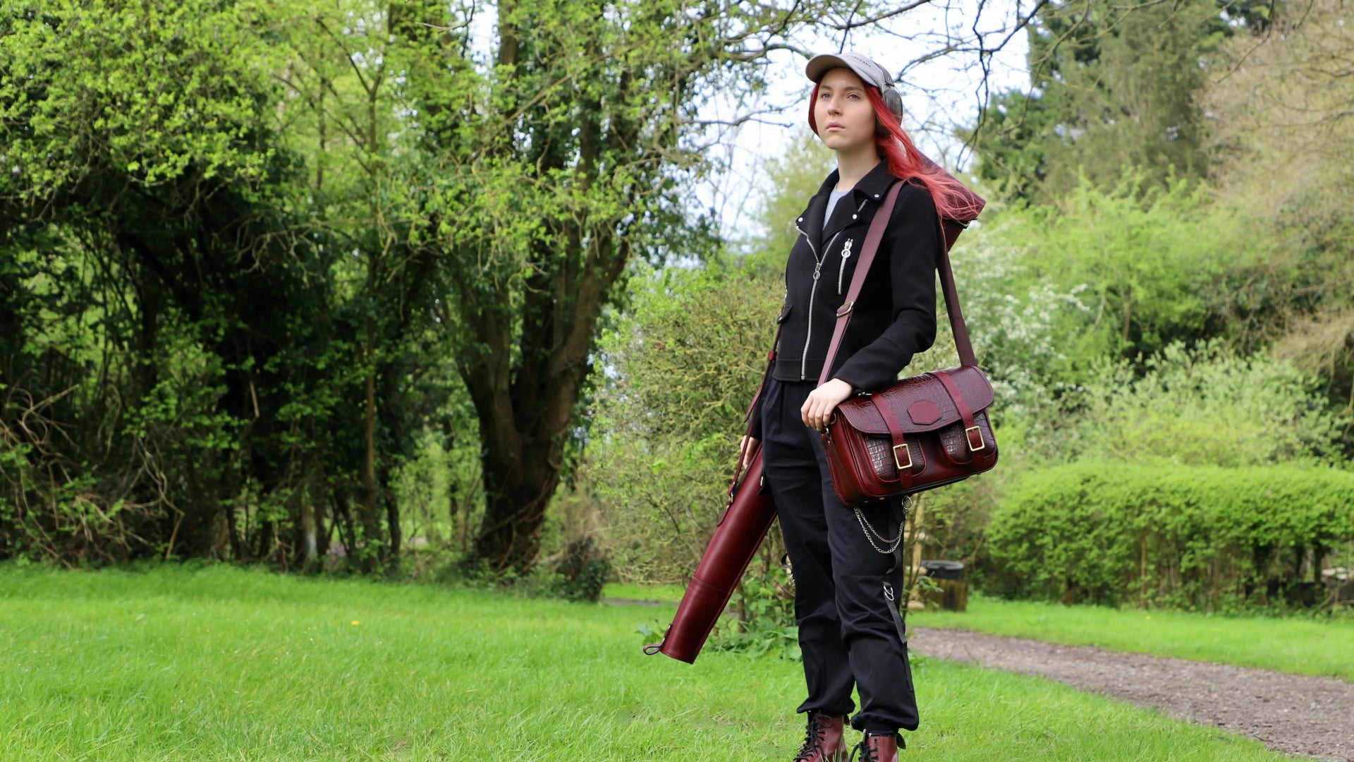 various shooting accessories on show. a woman in a park in london with a gun slip and cartridge bag over the shoulder and a howes and wayko shooting cap on