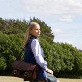 the hera kroko cartridge shooting bag on the shoulder of a woman in a field with trees in the background