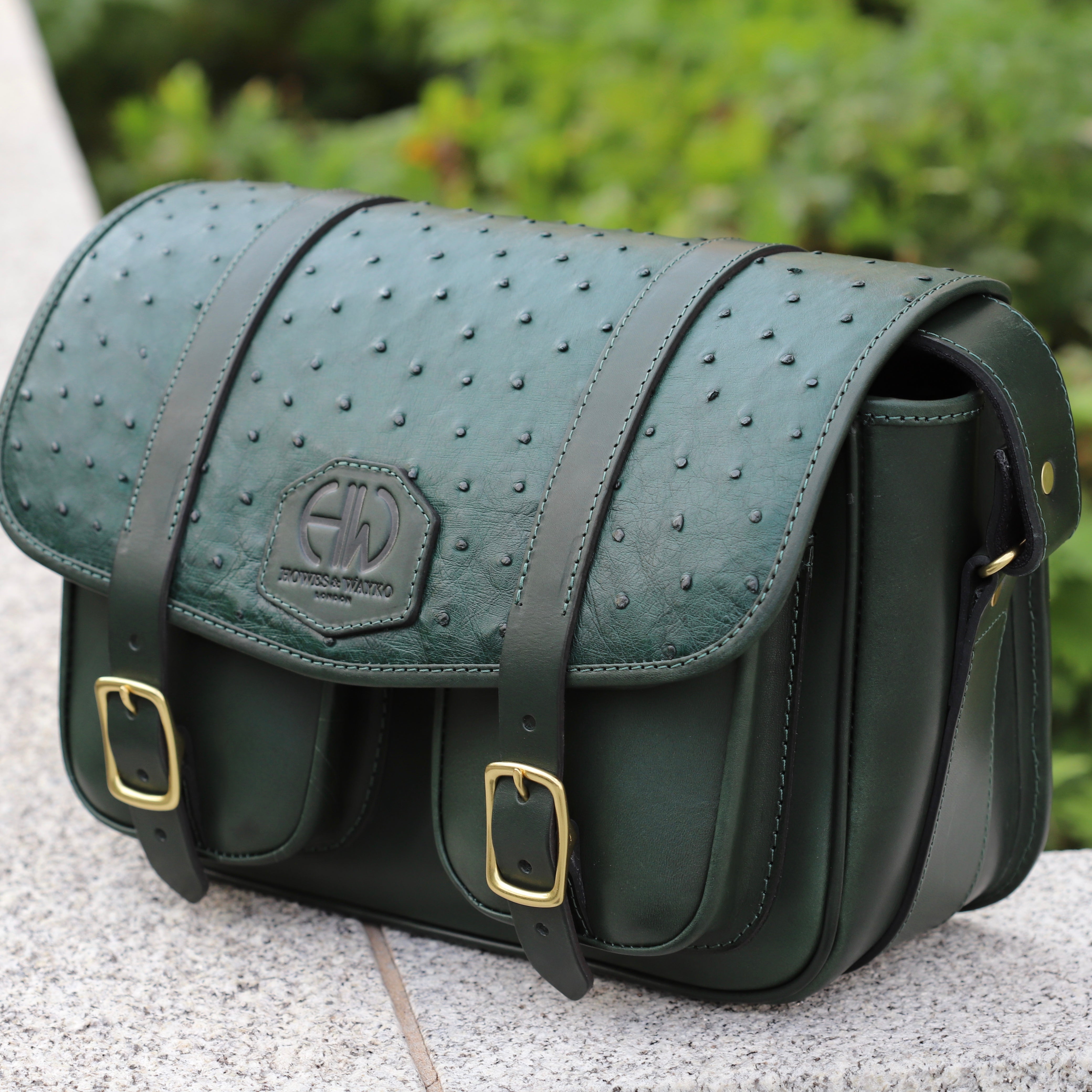 British Made Hera-Eden Green & Ostrich: Shooting Cartridge Bag side view on brick wall